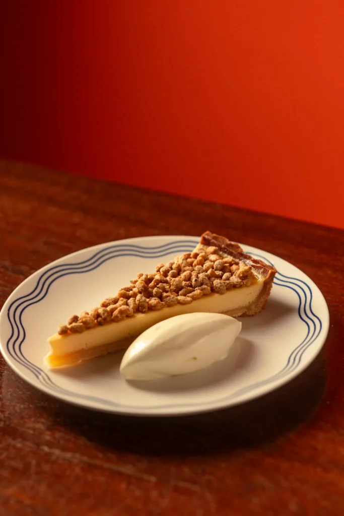 Slice of Italian cream tart with crumble topping and whipped cream at Matto in St George’s Bay