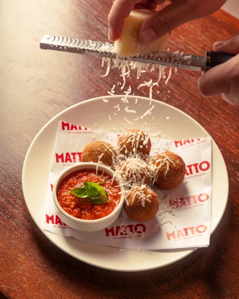 Grated cheese finished over Sicilian arancini with spicy tomato sauce at Matto in St George’s Bay
